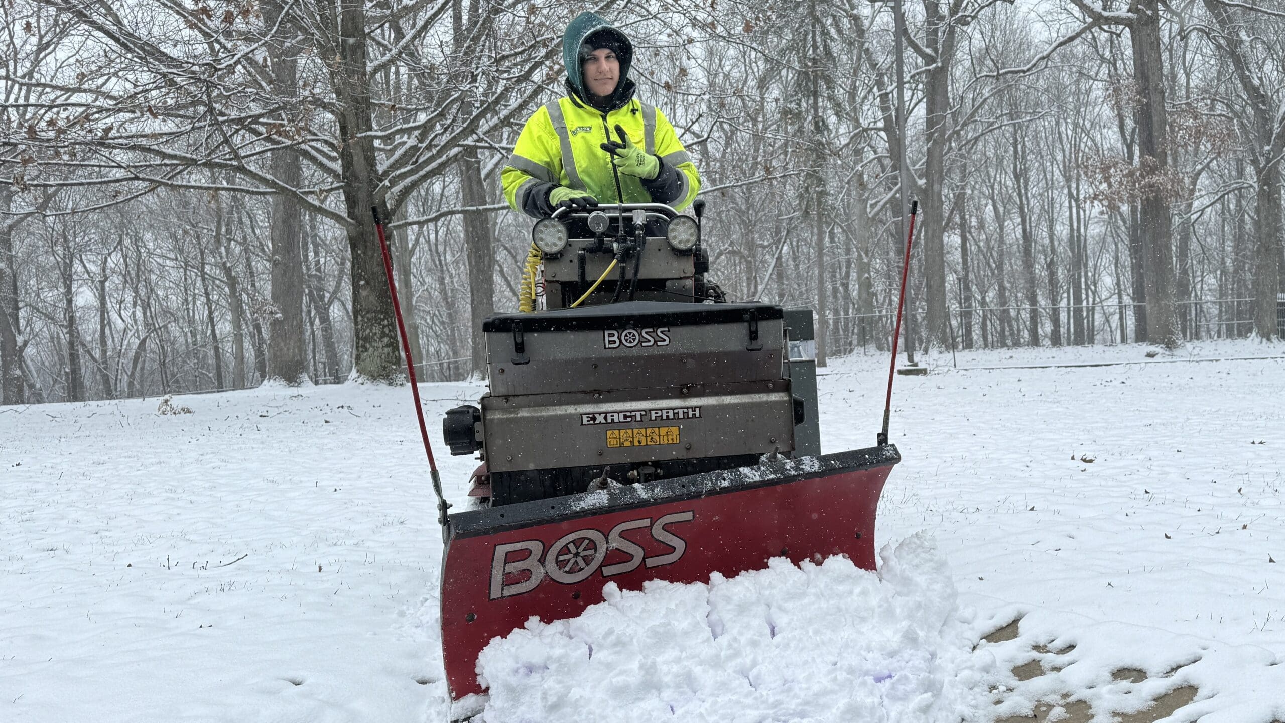Alt Text: Lily Silvis plowing a commercial property in Uniontown, PA, using a BOSS EXACT PATH Drop Spreader 1.5 with BOSS Plow Head Attachment