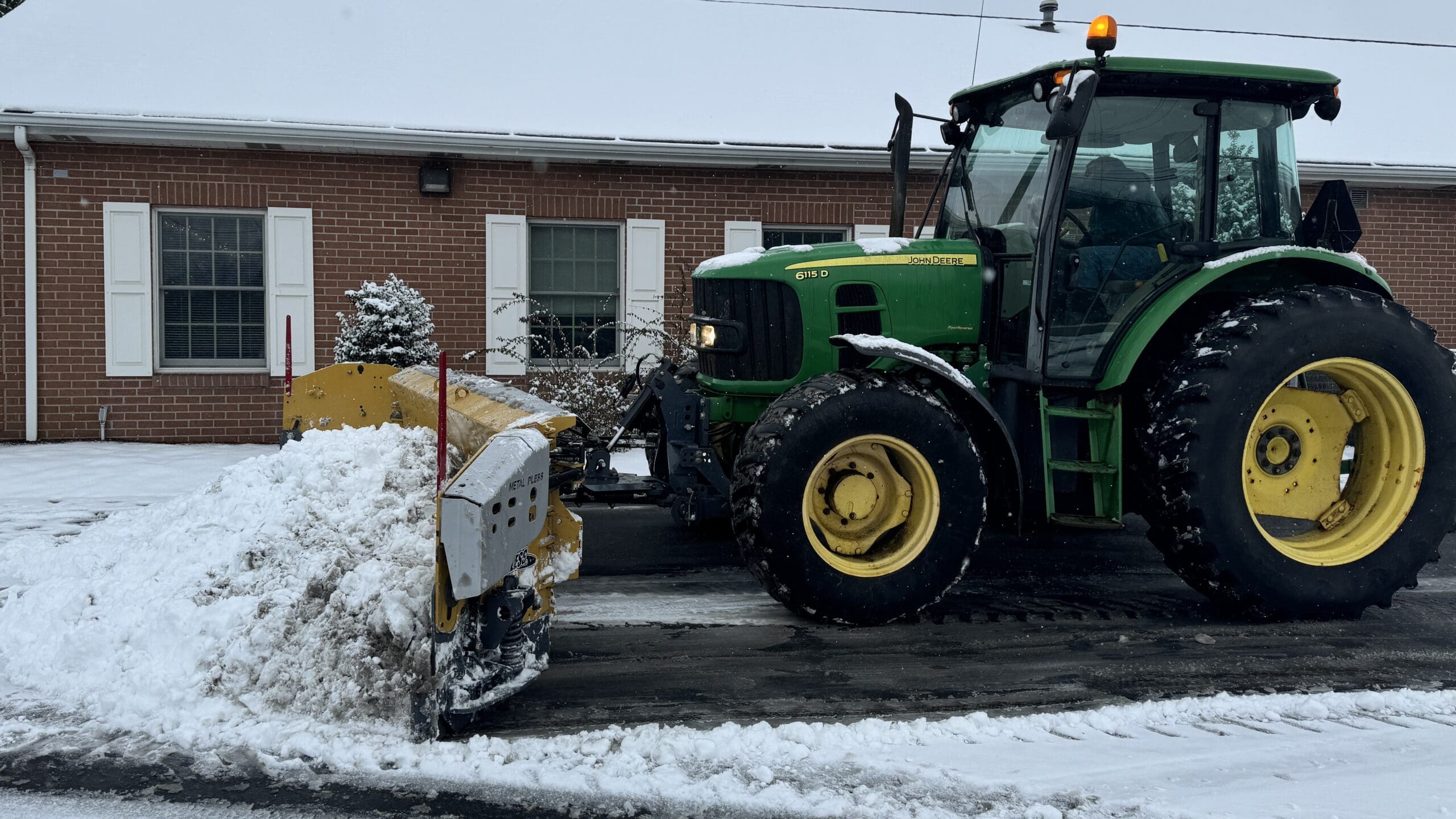 Alt Text: Lily Silvis plowing a commercial property in Mount Pleasant Pa using a John Deer Plow with a Sivis Group customized Metal Pless PlowMaxx PLSS 0830-13 LE Snow Plow Head